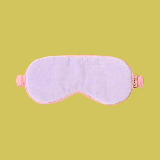 Kip & Co Lilac Velvet Eye Mask - Pale purple eye mask with pink trim on a green background