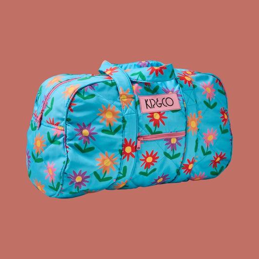 Floral-patterned duffel bag with 'KIP&CO' logo on a brown background