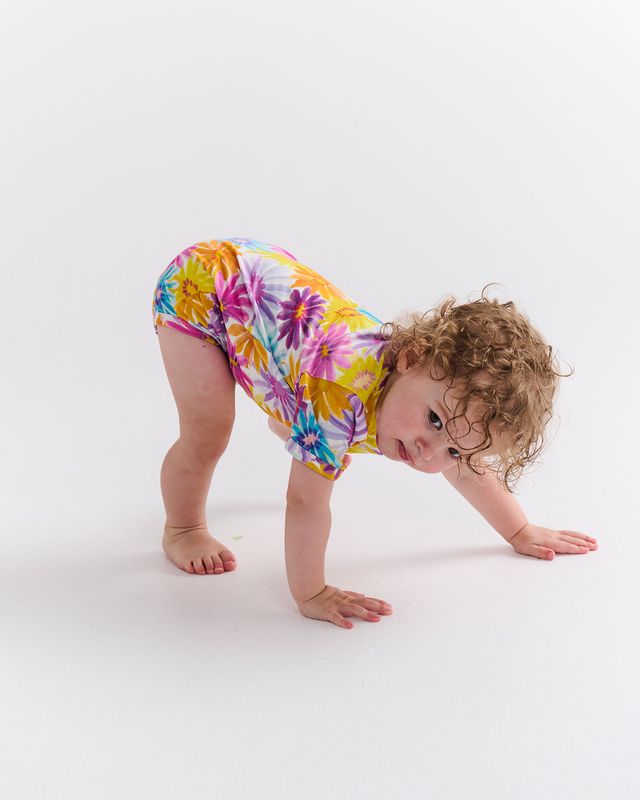 Child wearing a colorful floral onesie on a white background