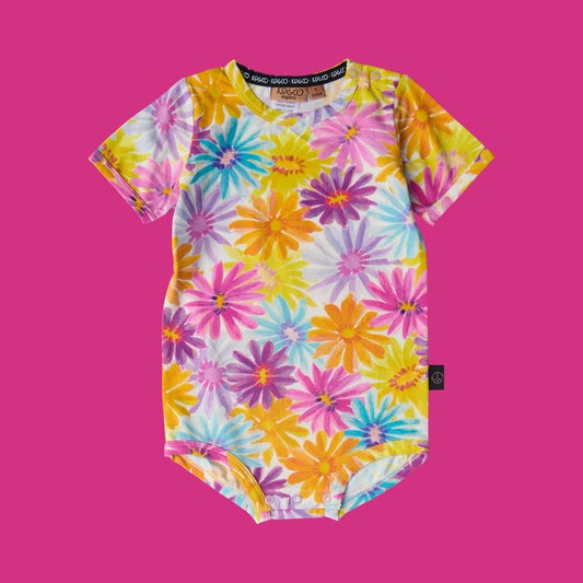 Kip & Co Petal Power Short Sleeve Romper - a colorful floral-patterned baby onesie on a pink background