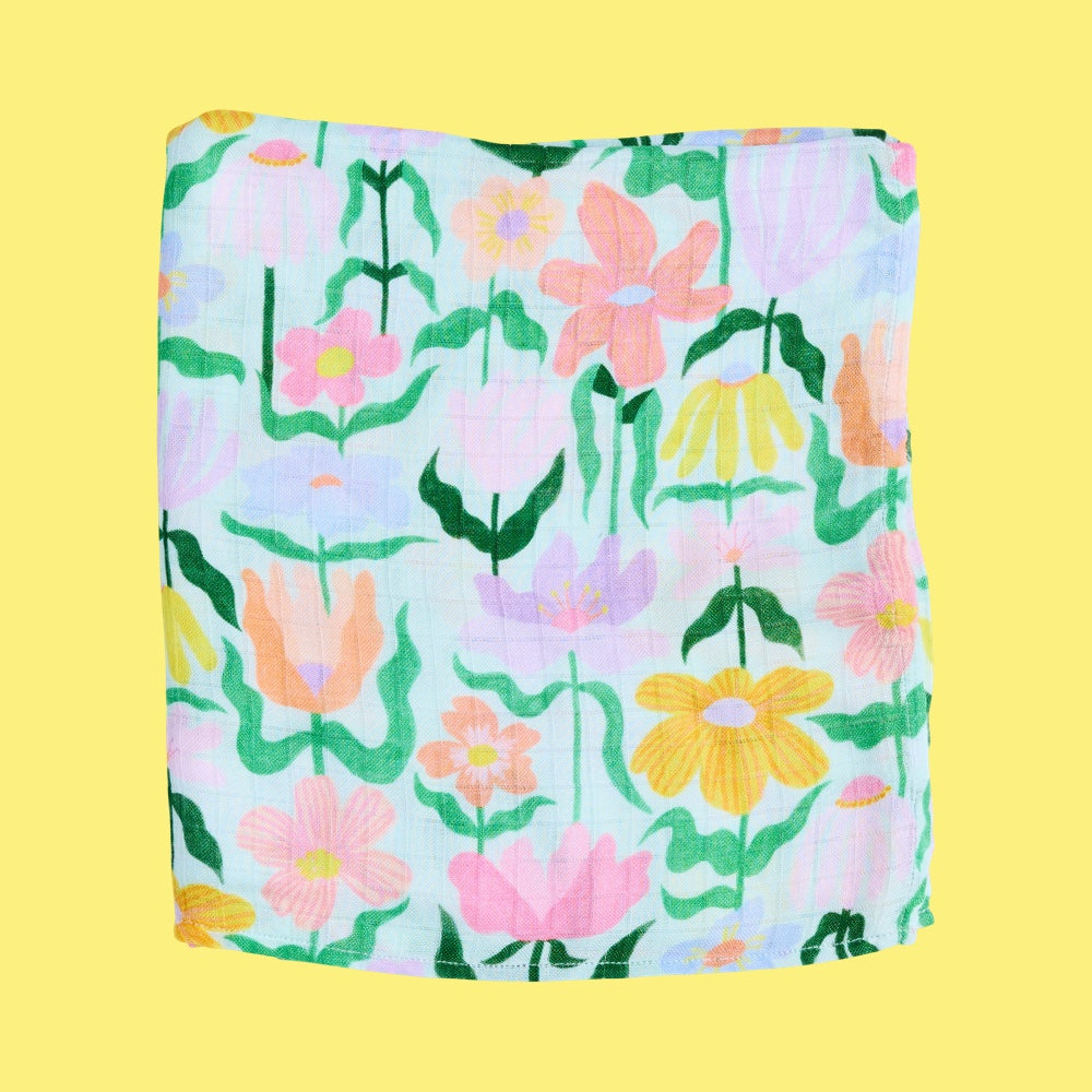 Floral patterned baby swaddle folded on a yellow background