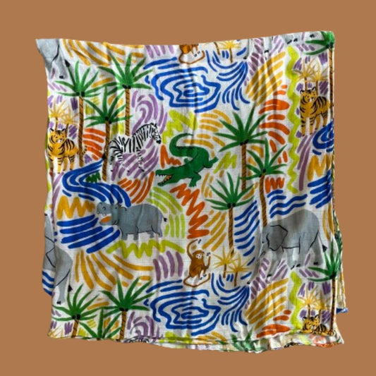 A folded swaddle featuring illustrations of the savannah including hippos, elephants, monkeys, tigers, crocodiles and zebras amongst palm trees and water.