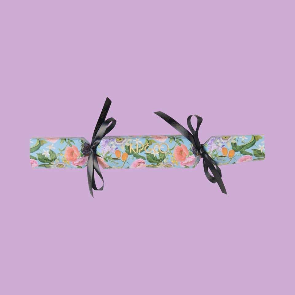 Packaging for Kip & Co Spring in the Air Velvet Eye Mask - Floral cracker with black ribbons on a purple background