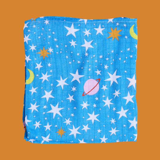 Folded baby swaddle with space-themed pattern on a brown background