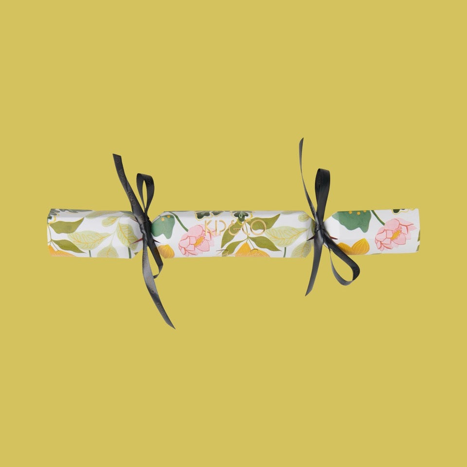 Packaging for Kip & Co Wander Velvet Eye Mask - Floral cracker with black ribbons on a yellow background