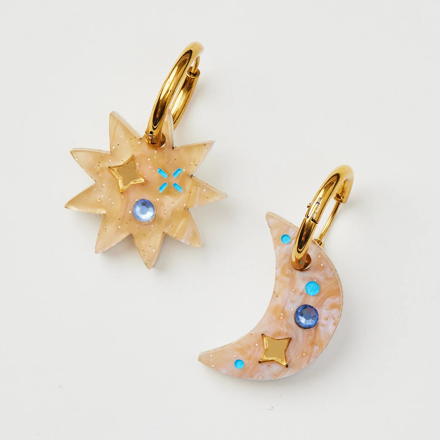 Pair of earrings with star and moon designs on a light background.