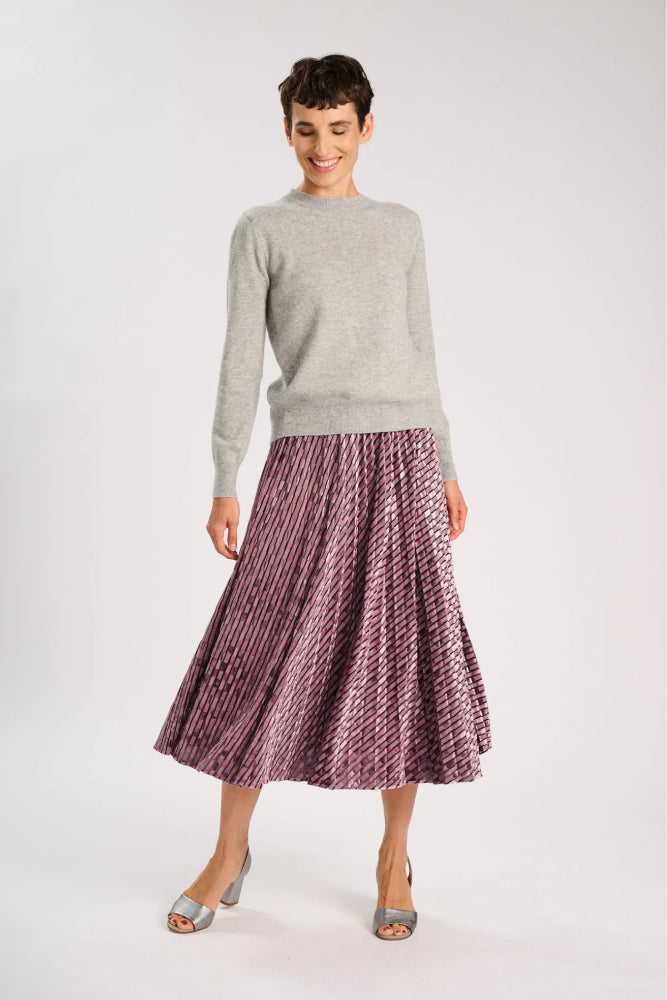 Model wearing a grey sweater and pale pink skirt on a white background