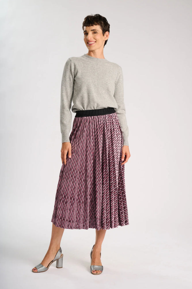 Model wearing a grey sweater and pale pink skirt on a white background