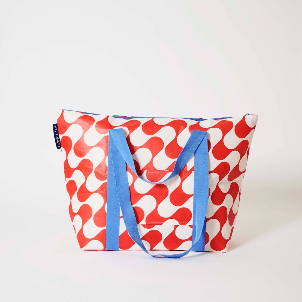 Project Ten Red Ripple Medium Zip Up Tote - a tote bag with a bold red and white wavy pattern and bright blue handles, photographed on a clean white studio background.