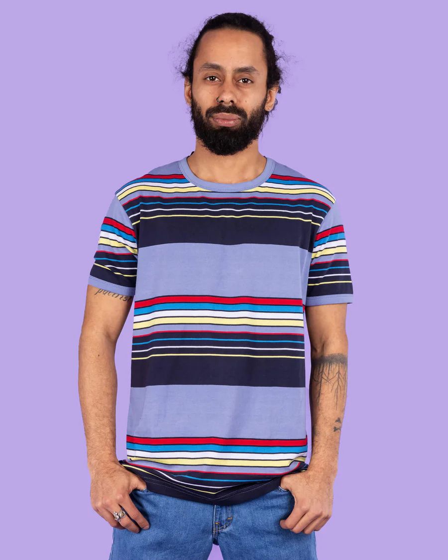 Model is wearing Run and Fly Blue Stripe Tee and smiling at camera.