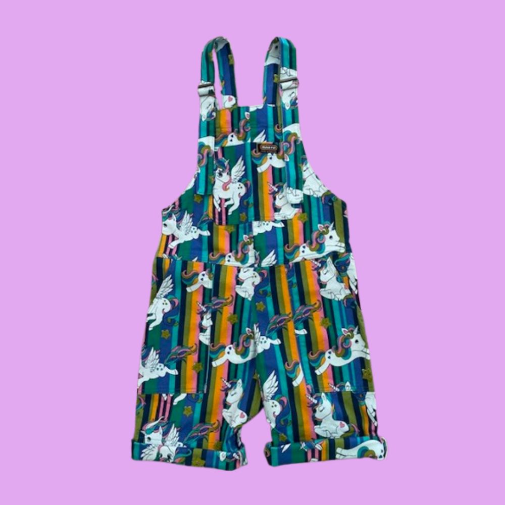 Short dungarees with cartoon unicorn pattern on a light purple background