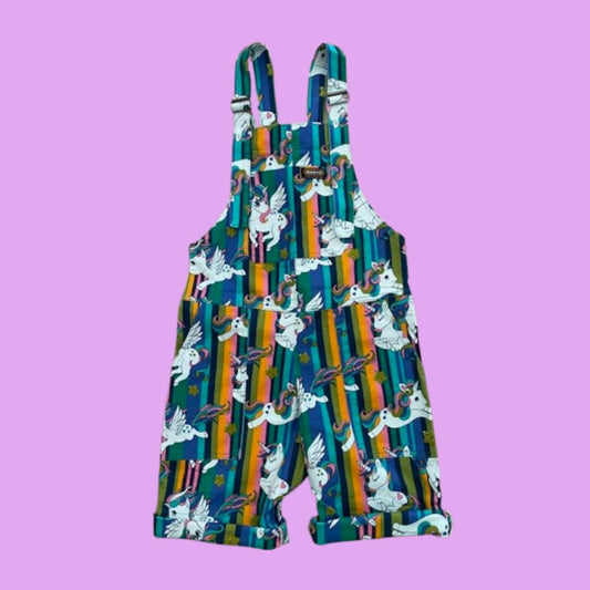 Short dungarees with cartoon unicorn pattern on a light purple background