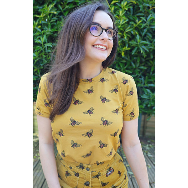 Person wearing a honey-coloured tee with bee print. 